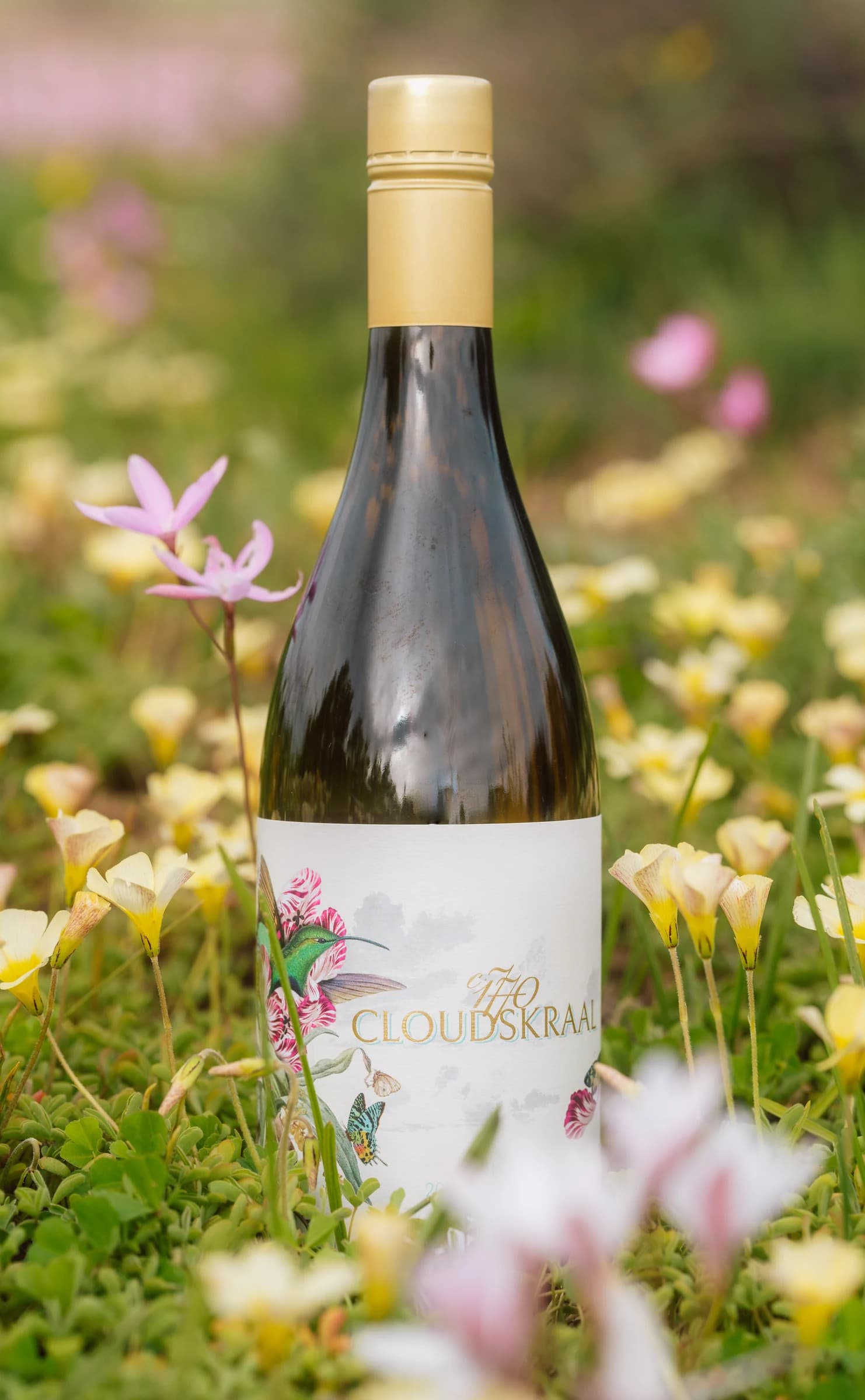 A bottle of Nieu Sauvignon Blanc standing among pink and white wildflowers